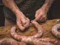Ręce wiążą kiełbasę sznurkiem. Zastanawiasz się, jak długo wędzić kiełbasę bez parzenia?