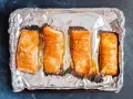 Cztery kawałki łososia pieczone na folii aluminiowej, gotowe do dalszego przygotowania, np. jak przygotować łososia do sushi.