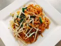 Pyszne danie Pad Thai z makaronem ryżowym, kiełkami fasoli mung, jajkiem i zieloną cebulką, polane charakterystycznym pad thai sosem.