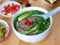 Aromatyczna zupa pho z wołowiną, makaronem ryżowym, świeżą kolendrą, chili i limonką. Obok talerzyki z dodatkami.