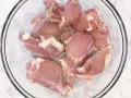 Surowe kawałki kurczaka w szklanej misce. Zastanawiasz się, ile waży udko bez kości?