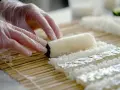 Ręce w rękawiczkach formują ryż na macie bambusowej. Przygotowanie zaprawy do sushi na 500g ryżu.