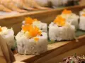 Roladki sushi z pomarańczową ikrą i chrupiącą posypką, idealne do słodkiego sosu do sushi.