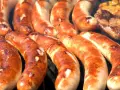 Kilka grubych, rumianych kiełbasek z grilla ułożonych obok siebie.