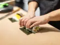 Ręce zwijają sushi na nori. Zastanawiasz się, nori gdzie kupić? W sklepach z azjatycką żywnością lub online.