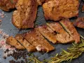 Seitan co to? Pokrojony w plastry, smażony seitan z przyprawami: różową solą, pieprzem i rozmarynem.