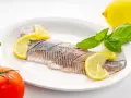 Filety śledzi z cytryną i bazylią na talerzu. Kto nie powinien jeść śledzi? Alergicy i osoby z problemami z cholesterolem.