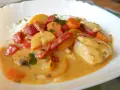 Kurczak curry z warzywami: kawałki kurczaka w kremowym sosie z papryką, marchewką i cukinią, podane z ryżem.