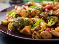 Pyszny stir fry z kurczakiem, brokułami i grzybami w sosie. Danie wygląda apetycznie i jest bogate w kolory.