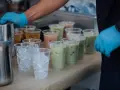 Przygotowanie do zrobienia kulek do bubble tea: ręce w niebieskich rękawiczkach, dzbanki, kubki z lodem i gotowe napoje.