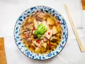 Aromatyczna zupa tom yum z kurczakiem i grzybami, ozdobiona chili i zieloną cebulką. Idealna na chłodne dni.