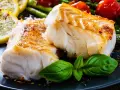 Dwa kawałki pieczonego dorsza atlantyckiego, podane z cytryną, szparagami i pomidorkami. Który lepszy?