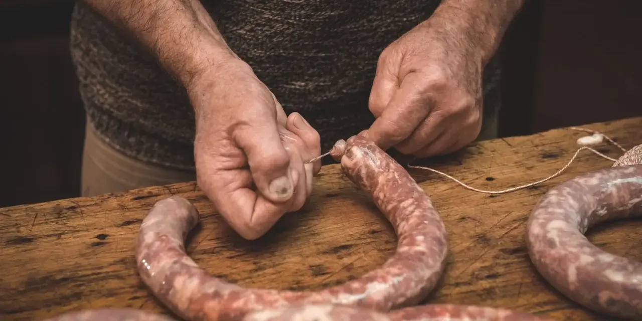 Ręce wiążą kiełbasę sznurkiem. Zastanawiasz się, jak długo wędzić kiełbasę bez parzenia?