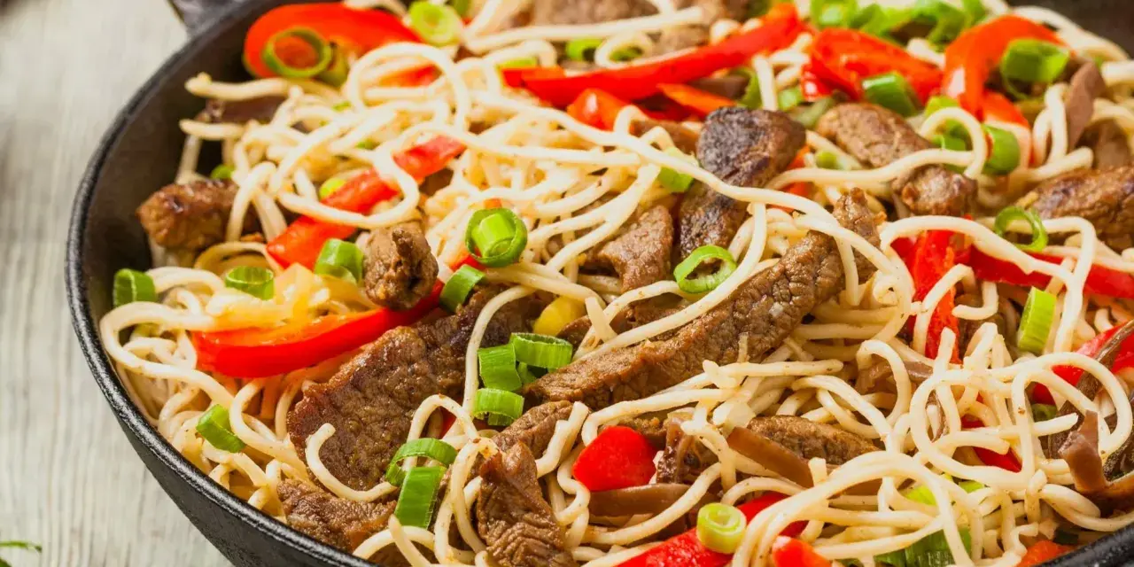 Makaron chow mein z wołowiną, papryką i szczypiorkiem w woku.