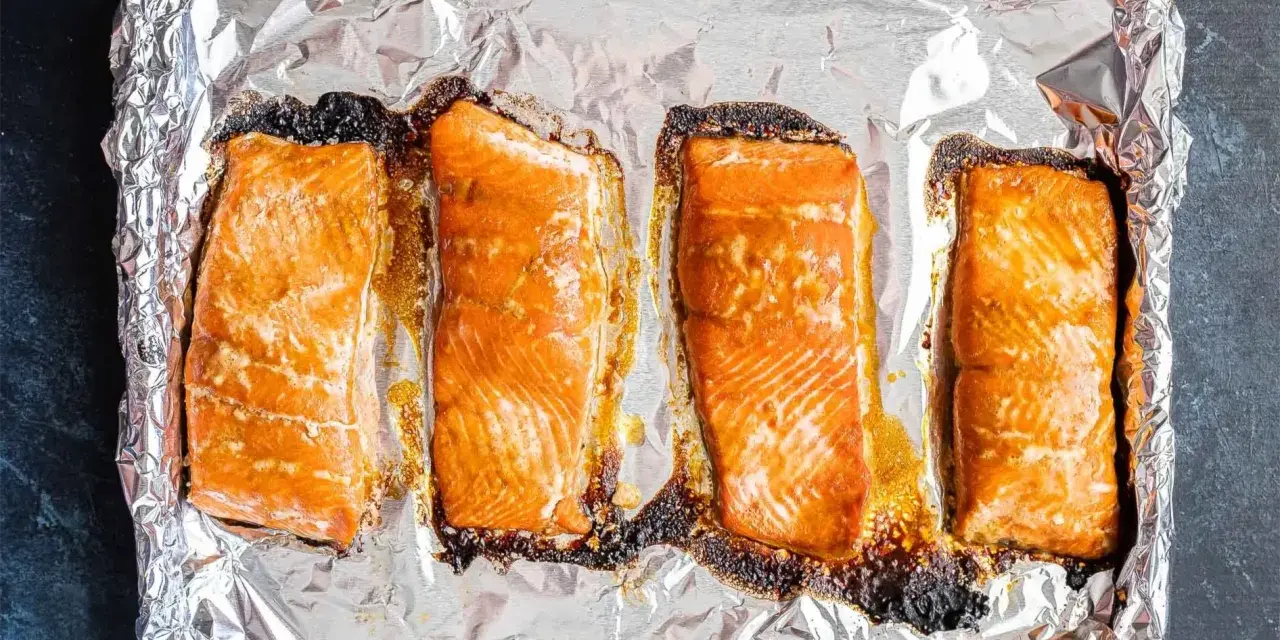 Cztery kawałki łososia pieczone na folii aluminiowej, gotowe do dalszego przygotowania, np. jak przygotować łososia do sushi.