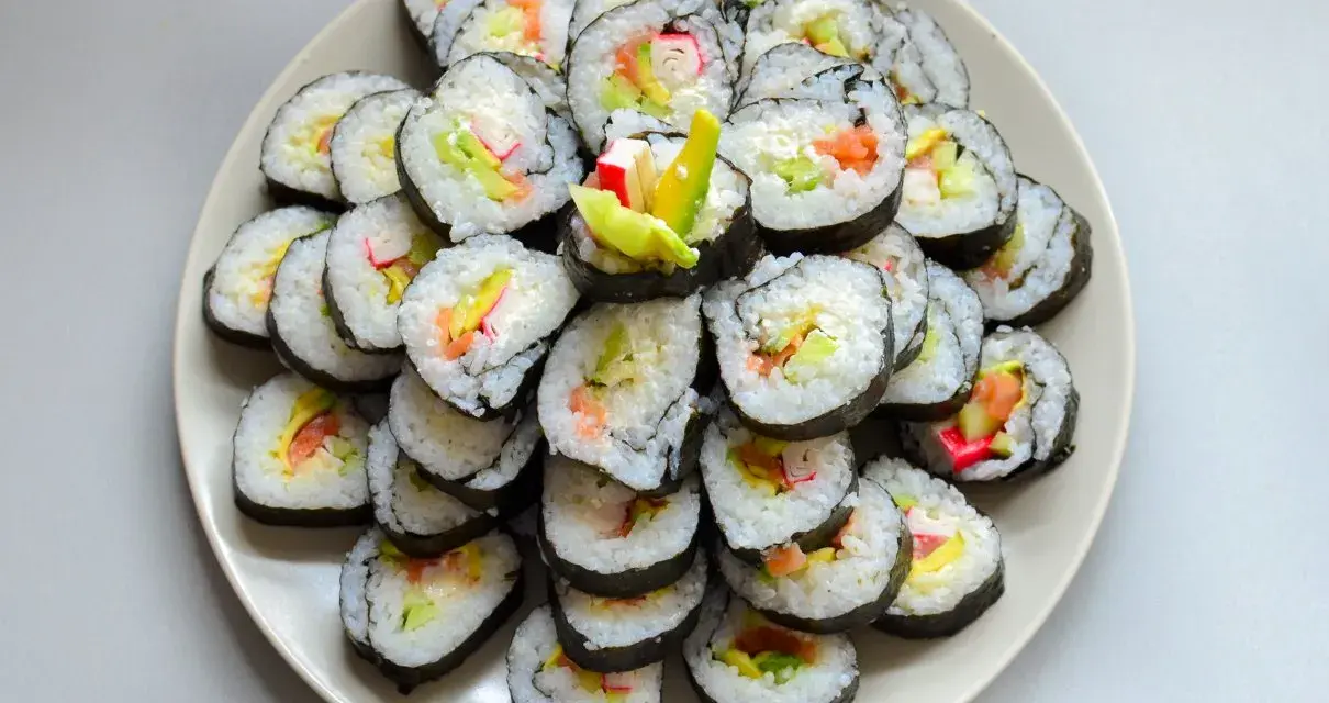 Talerz sushi z paluszkami krabowymi, awokado i łososiem. Idealne do nauki, jak przygotować paluszki krabowe do sushi.