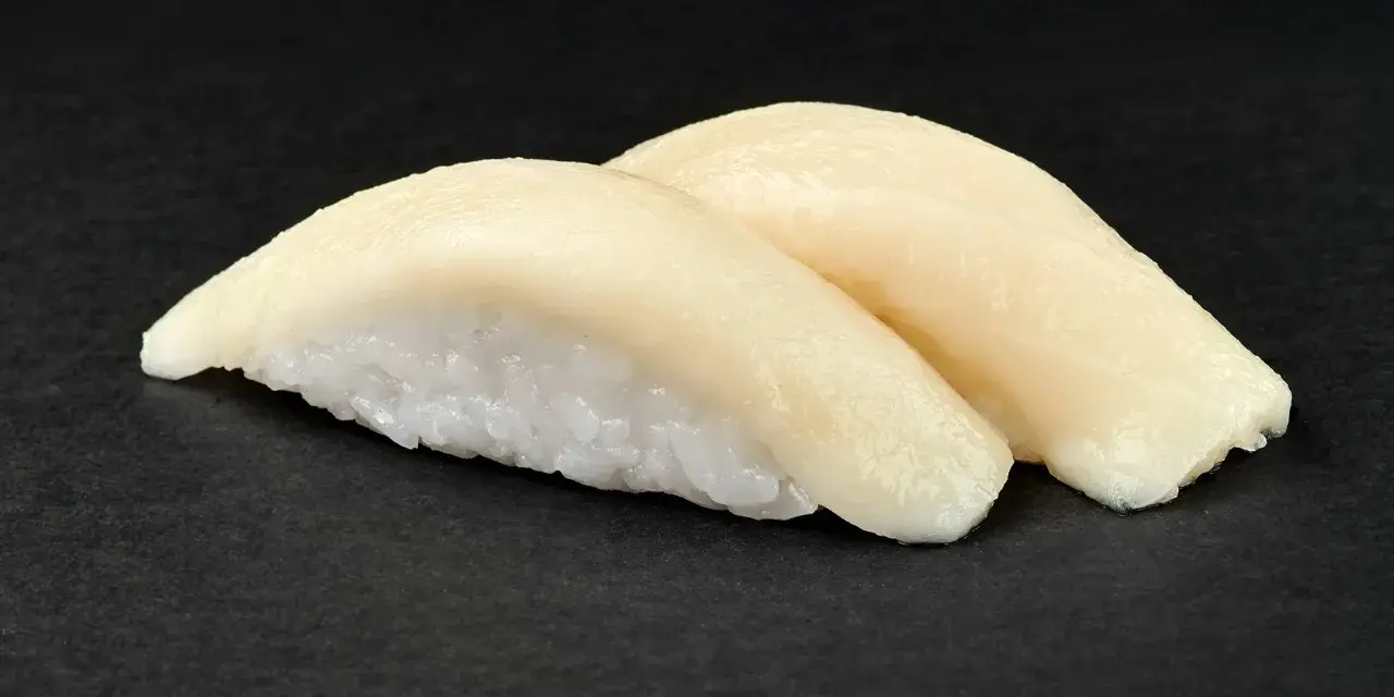 Dwa kawałki sushi z rybą maślaną na czarnym tle. Delikatna ryba idealnie komponuje się z ryżem.
