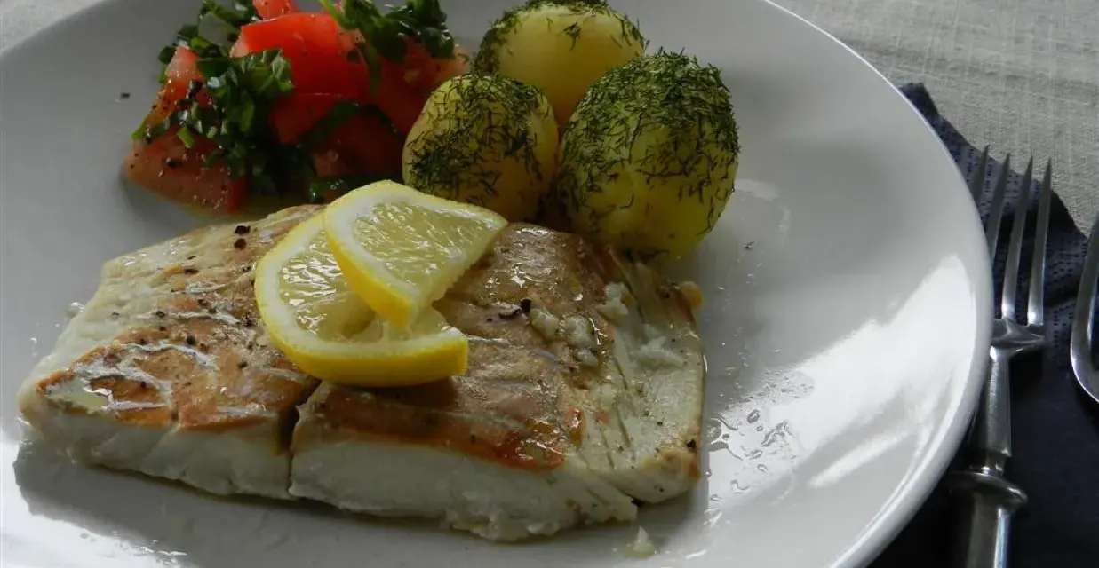 Filet z dorsza z piekarnika w folii, podany z ziemniakami i pomidorami.