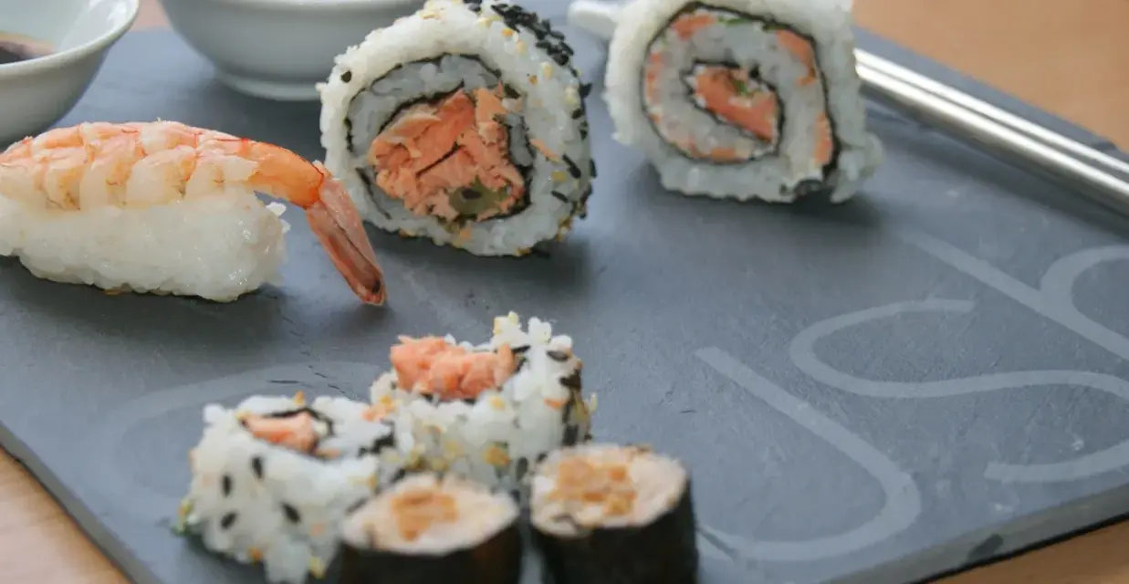 Jak przygotować krewetki do sushi? Na talerzu sushi z krewetką i rolkami z łososiem.
