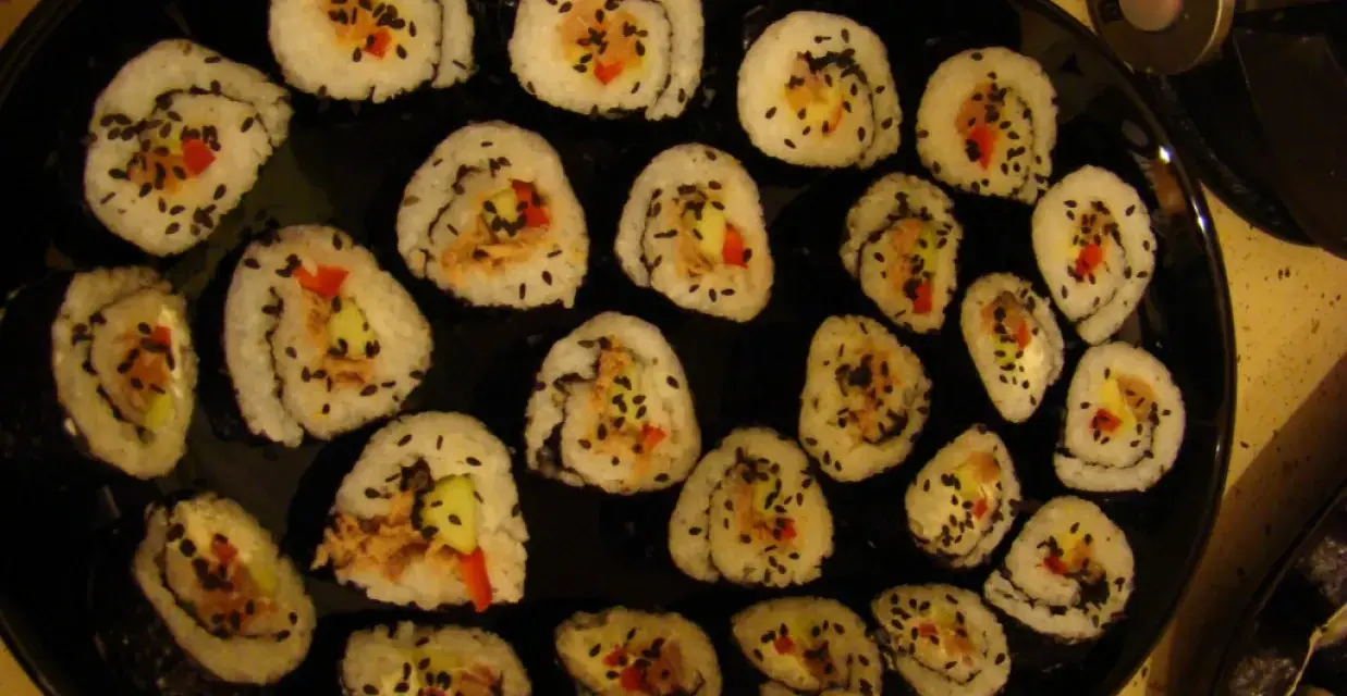 Roladki sushi z tuńczykiem, ogórkiem i papryką, posypane czarnym sezamem. Idealne, gdy zastanawiasz się, jak przygotować tuńczyka do sushi.