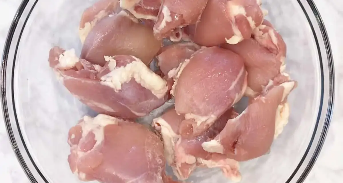Surowe kawałki kurczaka w szklanej misce. Zastanawiasz się, ile waży udko bez kości?