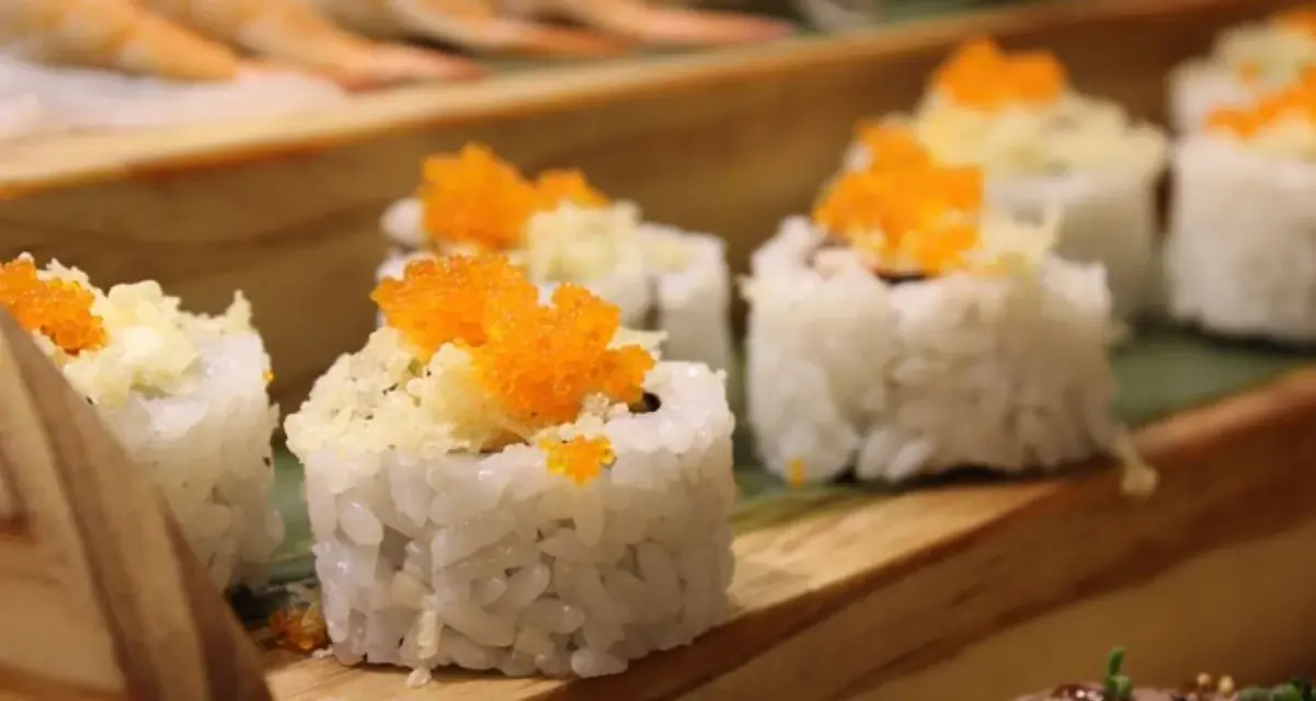 Roladki sushi z pomarańczową ikrą i chrupiącą posypką, idealne do słodkiego sosu do sushi.