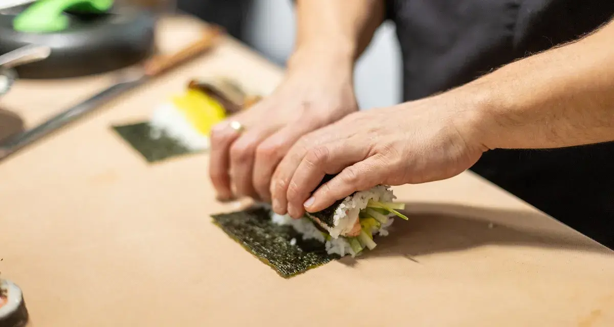 Ręce zwijają sushi na nori. Zastanawiasz się, nori gdzie kupić? W sklepach z azjatycką żywnością lub online.