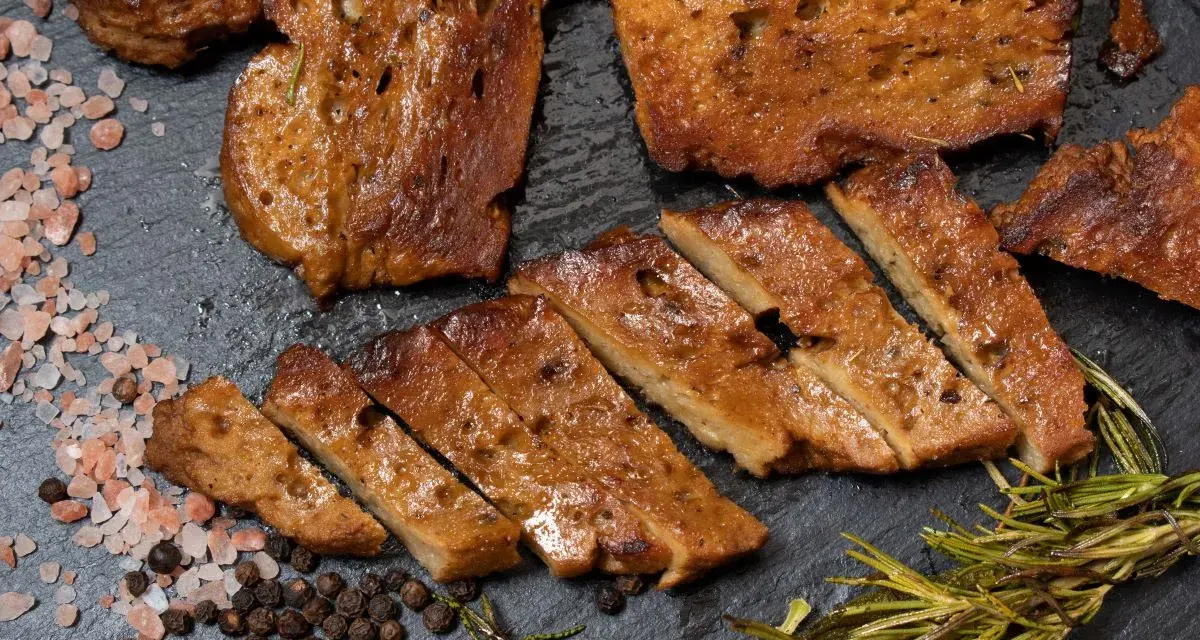 Seitan co to? Pokrojony w plastry, smażony seitan z przyprawami: różową solą, pieprzem i rozmarynem.