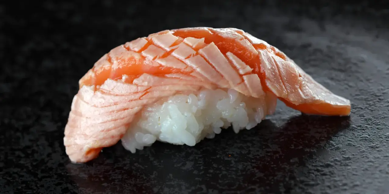 Jak wygląda sushi: delikatny ryż i soczysty, lekko opalony łosoś ułożony w wachlarz.
