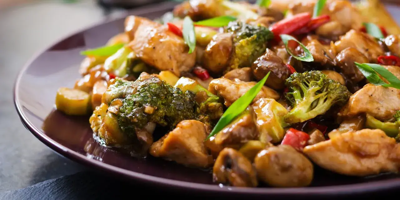 Pyszny stir fry z kurczakiem, brokułami i grzybami w sosie. Danie wygląda apetycznie i jest bogate w kolory.