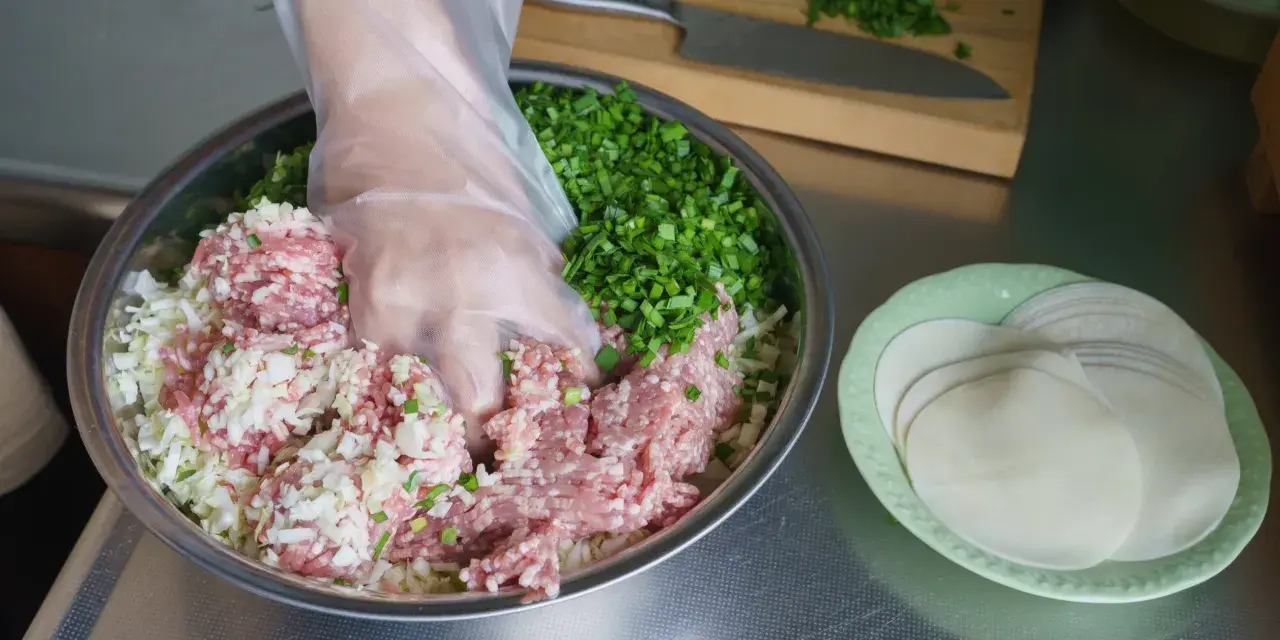 Mieszanie mielonego mięsa, kapusty i szczypiorku do pierożków gyoza. Przepis na pyszne domowe pierożki.