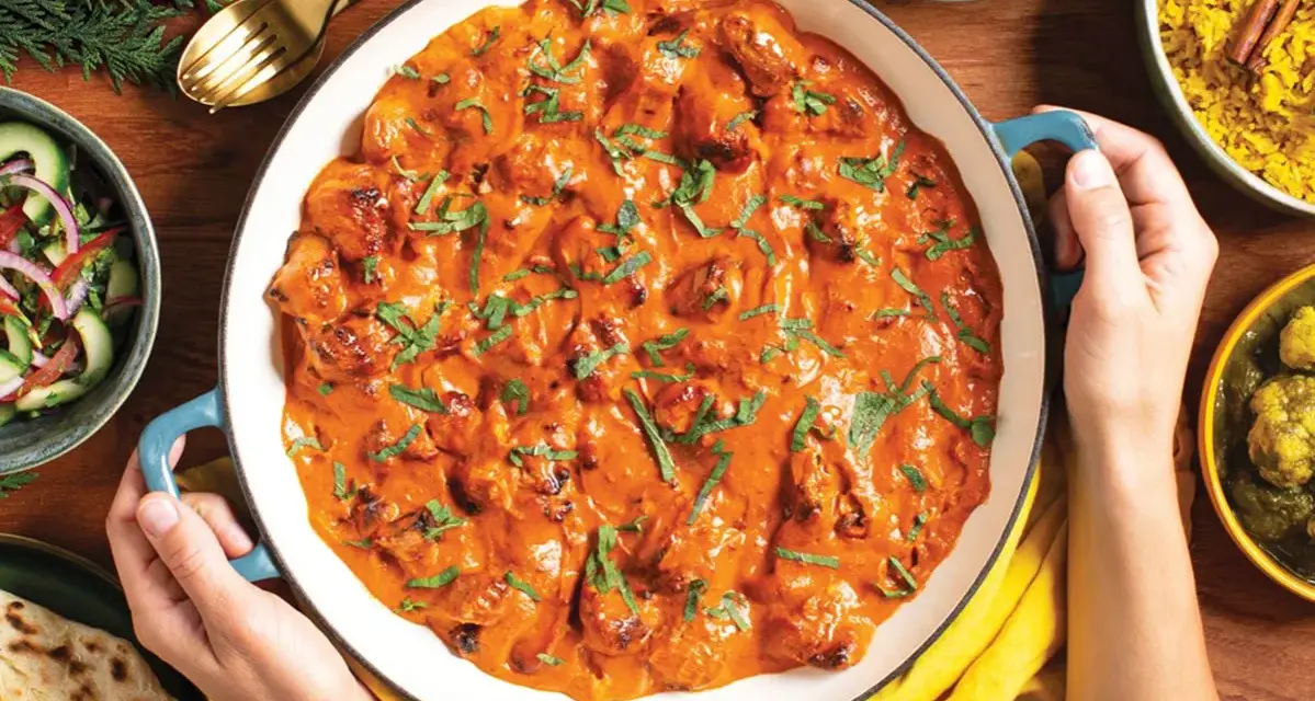 Pyszny **butter chicken przepis oryginalny** w kremowym sosie, podany z ryżem, sałatką i chlebkiem naan.