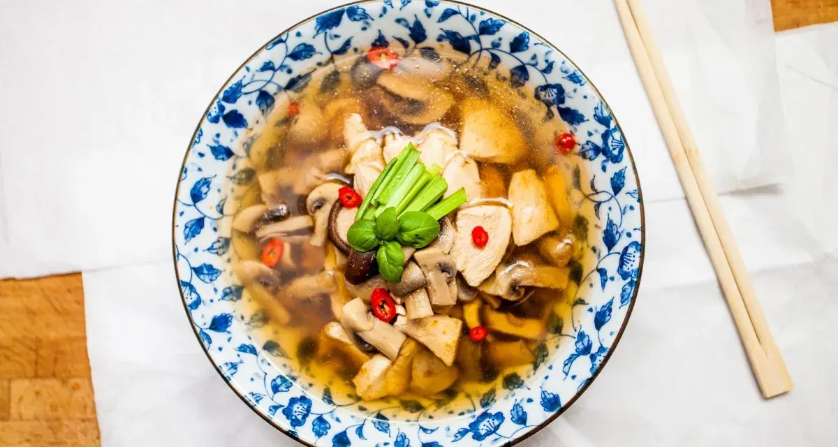 Aromatyczna zupa tom yum z kurczakiem i grzybami, ozdobiona chili i zieloną cebulką. Idealna na chłodne dni.