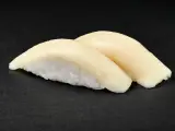 Dwa kawałki sushi z rybą maślaną na czarnym tle. Delikatna ryba idealnie komponuje się z ryżem.