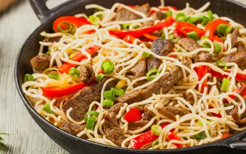 Makaron chow mein z wołowiną, papryką i szczypiorkiem w woku.