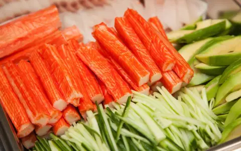 Paluszki surimi, pokrojony ogórek i awokado. Idealne składniki do sushi, które wyjaśniają, surimi co to jest.