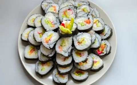 Talerz sushi z paluszkami krabowymi, awokado i łososiem. Idealne do nauki, jak przygotować paluszki krabowe do sushi.