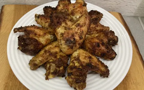 Chrupiące skrzydełka z airfryer ułożone na białym talerzu, apetycznie przypieczone i gotowe do podania.