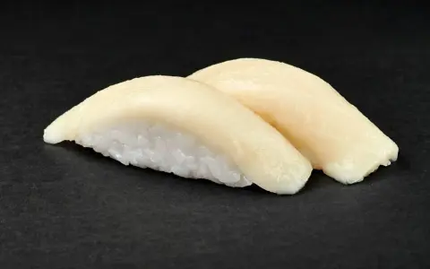 Dwa kawałki sushi z rybą maślaną na czarnym tle. Delikatna ryba idealnie komponuje się z ryżem.