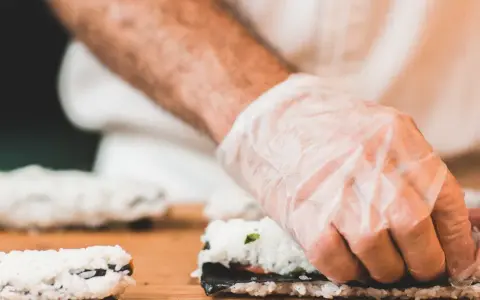 Ręce w rękawiczkach zwijają sushi. Zastanawiasz się, jaka ryba do sushi będzie najlepsza?