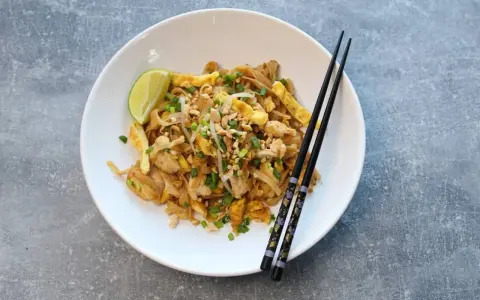 Pyszny pad thai oryginalny przepis z kurczakiem, jajkiem, orzeszkami i limonką.