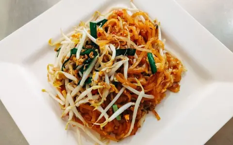 Pyszne danie Pad Thai z makaronem ryżowym, kiełkami fasoli mung, jajkiem i zieloną cebulką, polane charakterystycznym pad thai sosem.