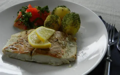 Filet z dorsza z piekarnika w folii, podany z ziemniakami i pomidorami.