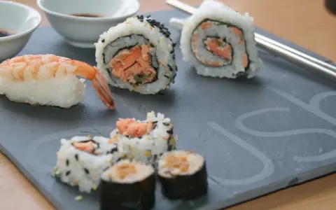 Jak przygotować krewetki do sushi? Na talerzu sushi z krewetką i rolkami z łososiem.