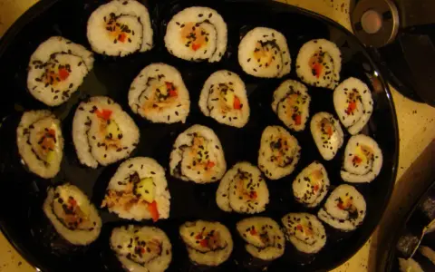 Roladki sushi z tuńczykiem, ogórkiem i papryką, posypane czarnym sezamem. Idealne, gdy zastanawiasz się, jak przygotować tuńczyka do sushi.