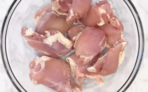 Surowe kawałki kurczaka w szklanej misce. Zastanawiasz się, ile waży udko bez kości?