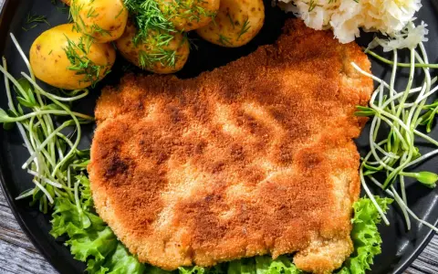 Chrupiący schabowy w panko, podany z młodymi ziemniaczkami, surówką i świeżą sałatą. Prawdziwa uczta dla podniebienia!