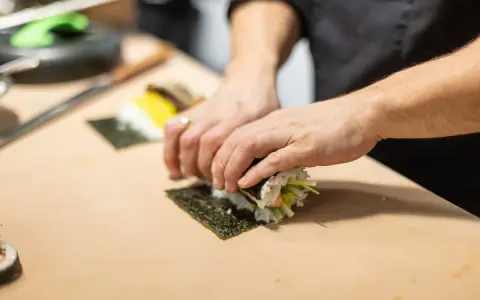 Ręce zwijają sushi na nori. Zastanawiasz się, nori gdzie kupić? W sklepach z azjatycką żywnością lub online.