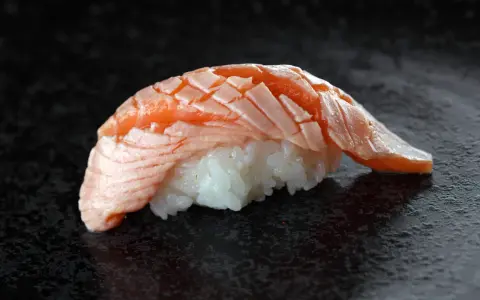 Jak wygląda sushi: delikatny ryż i soczysty, lekko opalony łosoś ułożony w wachlarz.