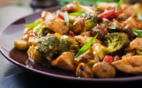 Pyszny stir fry z kurczakiem, brokułami i grzybami w sosie. Danie wygląda apetycznie i jest bogate w kolory.